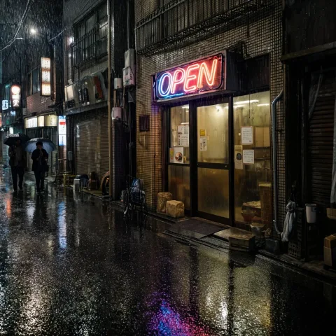 A neon sign reading OPEN above the doorway of a small noodle shop in a rainy Tokyo alley at night, reflections on the wet asphalt, a few passers-by with umbrellas, cinematic, photorealistic.